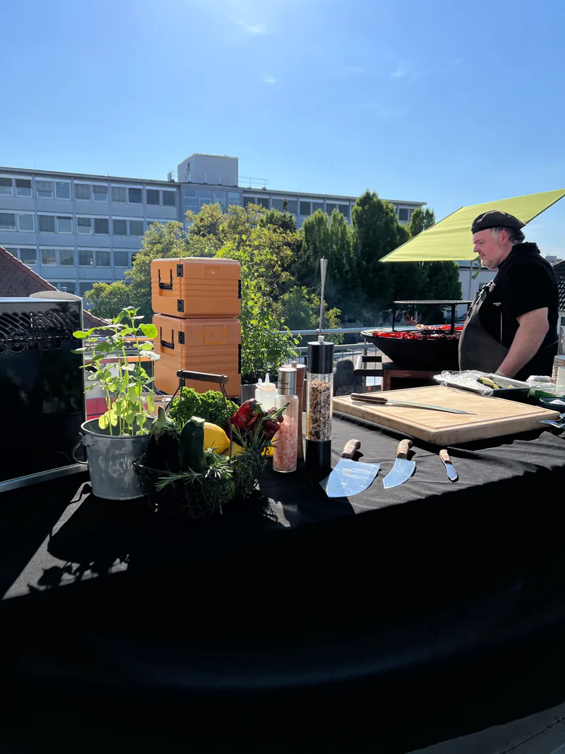 Spieße über der Glut, im Hintergrund die Feuerstelle