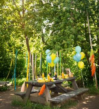 Birthday picnic table decorated with balloons in a garden